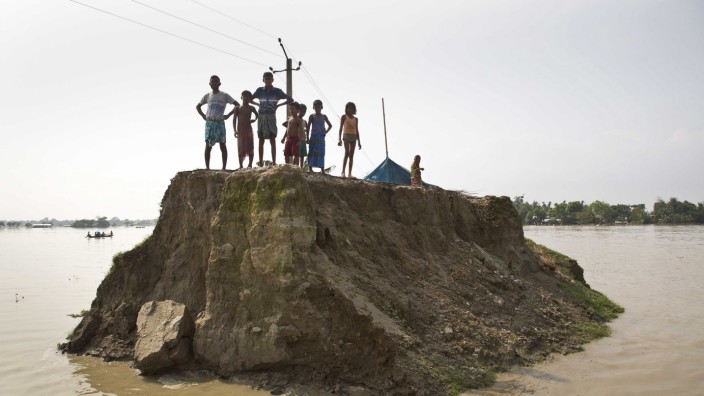 Das Politische Buch: Symbol der Zukunft? Dorfbewohner warten auf einer von den Überschwemmungen zerstörten Straße in Guwahati (Indien) auf Hilfsgüter - und auf ein besseres Leben.
