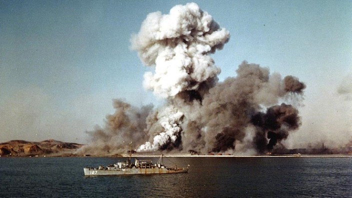 Smoke rises over Hungnam's port area, as facilties and remaining U.N. supplies are demolished by explosives on the final day of evacuation operations