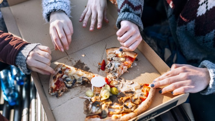 Four friends eating pizza outdoors partial view model released Symbolfoto PUBLICATIONxINxGERxSUIxAU