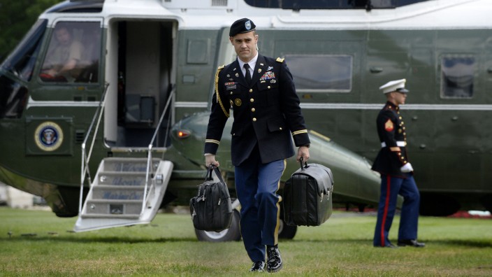 USA: Ein Offizier trägt den „Football“, den Koffer mit den nuklearen Einsatzplänen, Startcodes und einem Telefon vor dem Hubschrauber des Präsidenten über den Rasen.