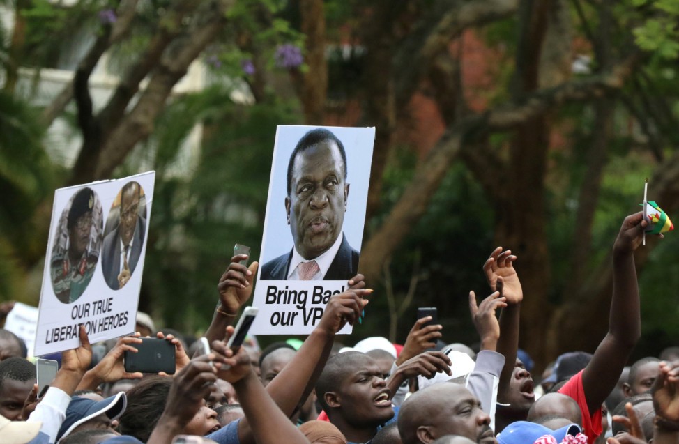 Protesters hold posters showing support for ousted Zimbabwean vice-President Emmerson Mnangagwa, in Harare