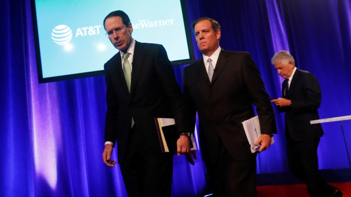 Chief Executive Officer of AT&T Randall Stephenson walks off the stage with David McAtee, SEVP and General Counsel for AT&T, and Daniel Petrocelli, counsel from O'Melveny & Myers LLP., after a press conference in New York City