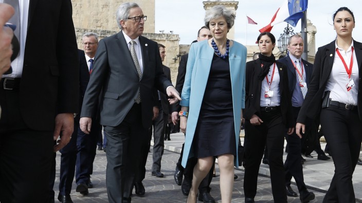 British Prime Minister May and European Commission President Juncker walk during a break in the European Union leaders summit in Malta