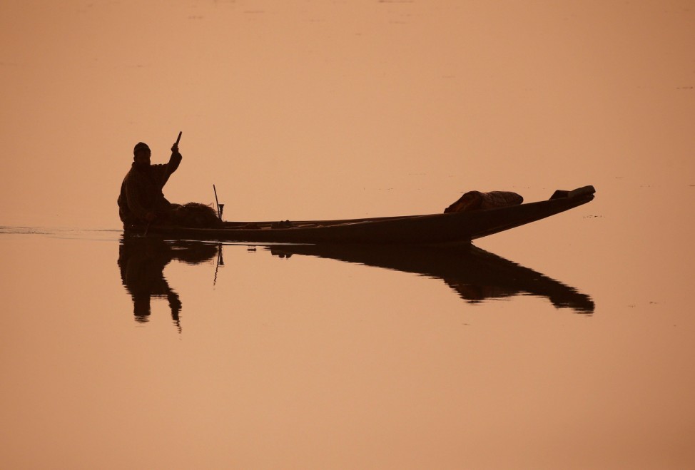 A fisherman rows his boat through the waters of the Dal Lake on a cold morning in Srinagar