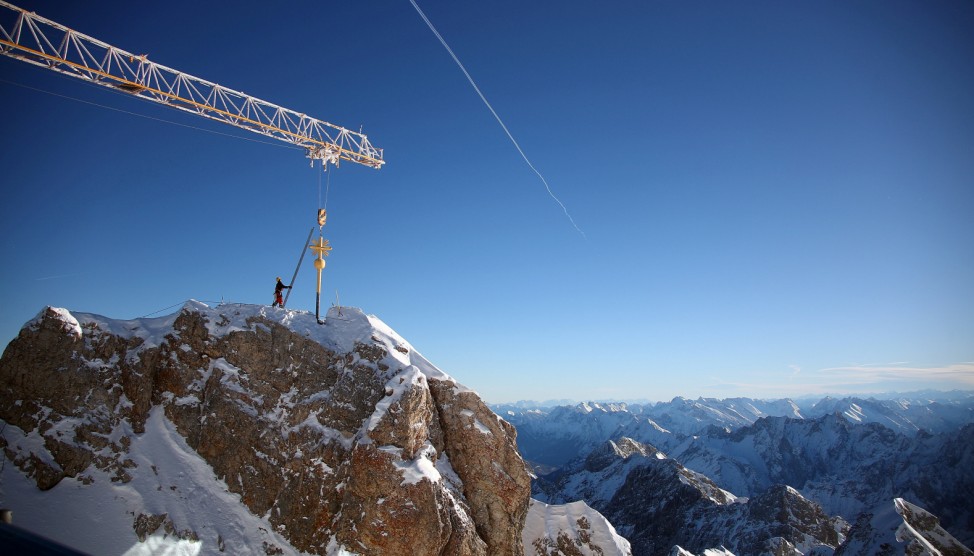A worker fixes the renovated summit cross on top of the Zugspitze