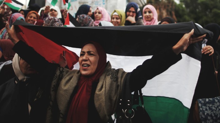 A woman holds a Palestinian flag during a protest against the U.S. intention to move its embassy to Jerusalem and to recognize the city of Jerusalem as the capital of Israel, in Gaza City