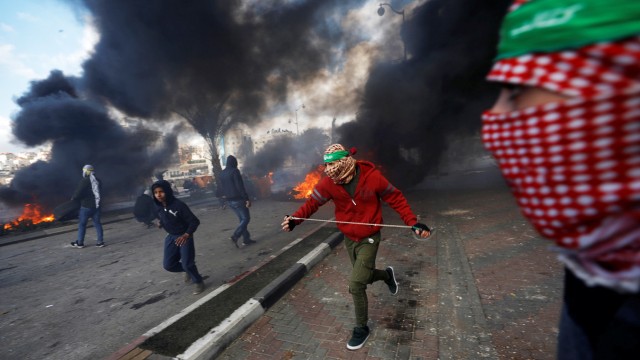 Palestinian protesters run during clashes with Israeli troops at a protest against U.S. President Donald Trump's decision to recognize Jerusalem as the capital of Israel, near the Jewish settlement of Beit El, near the West Bank city of Ramallah