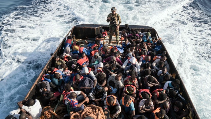 Mittelmeer: Ein Mitglied der libyschen Küstenwache mit geretteten Flüchtlingen. Vielen Migranten drohen in dem Land katastrophale Zustände.
