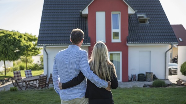 Happy couple standing arm in arm in the garden looking at their house model released Symbolfoto prop