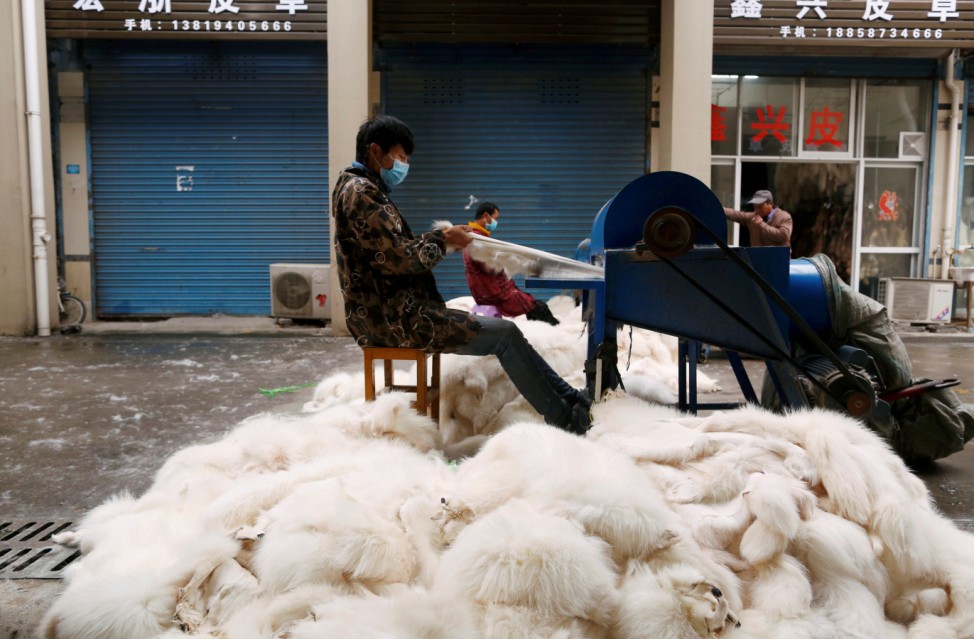 Workers process fox fur with machinery at a fur market in Chongfu