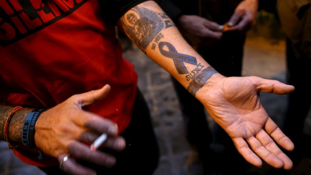 Paul Levely, a child sex abuse victim, wears a t-shirt that says 'no more silence' and shows a tattoo on his arm as he stands in front of the Quirinale hotel in Rome