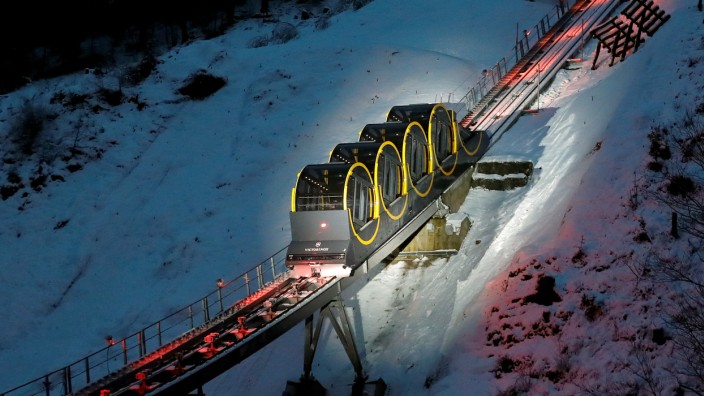 The barrel-shaped carriages of a new funicular line are seen on the illuminated track near Stoos