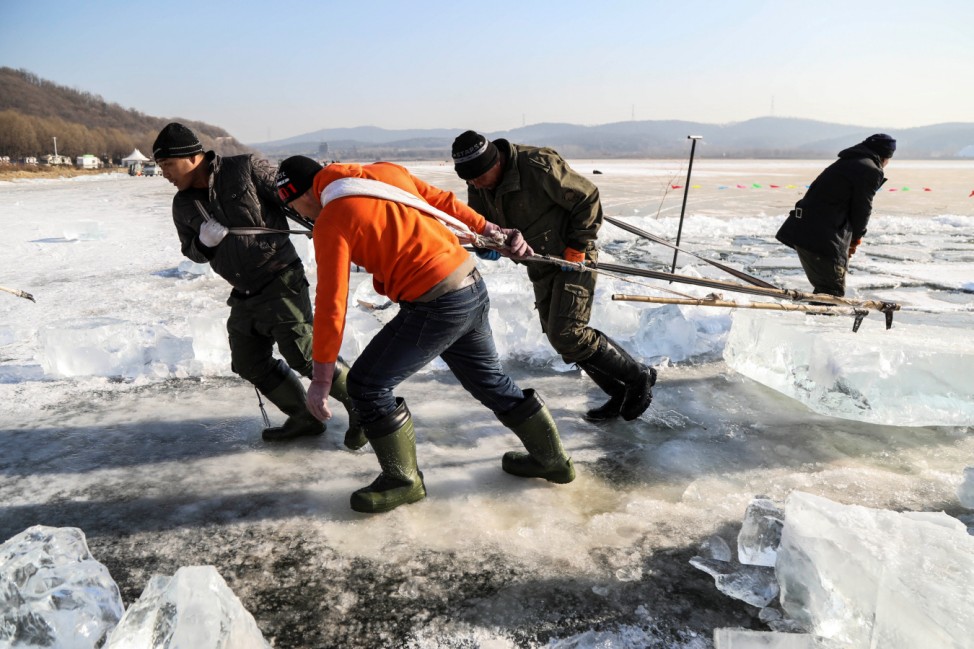 Workers extract giant ice cubes from the frozen Xiu lake at the Qipan mountain in Shenyang