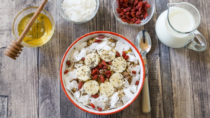Bowl of muesli with banana slices chia seeds coconut chips and goji berries PUBLICATIONxINxGERxSUI