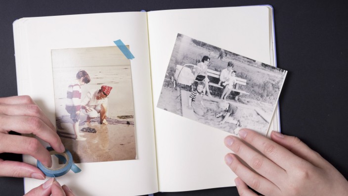 Two people sticking old fotographs in album model released Symbolfoto PUBLICATIONxINxGERxSUIxAUTxHUN