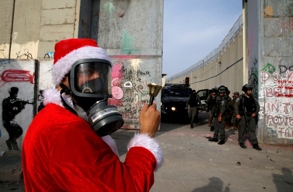 Palestinian dressed as Santa Claus stands in front of Israeli troops during a protest in the West Bank city of Bethlehem