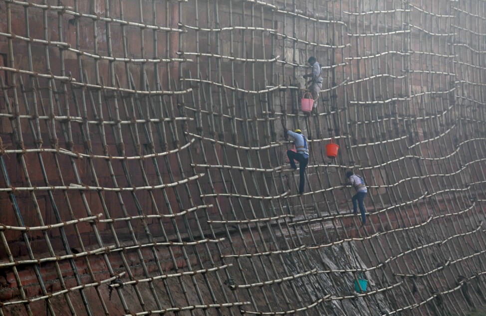 Workers climb scaffolding to clean the walls of the historic Red Fort in the old quarters of Delhi