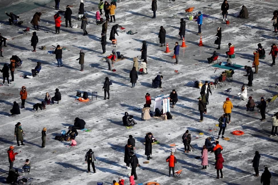 People fish for trout on a frozen river during the Ice Festival in Hwacheon