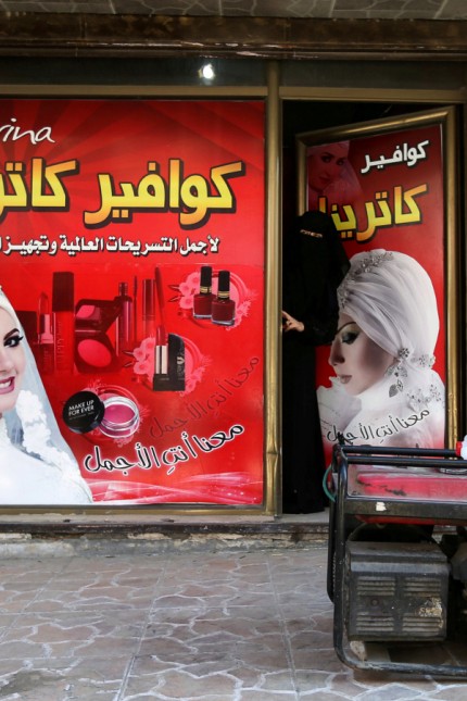 A Palestinian woman looks out of a hairstyle salon as a generator is seen outside in the southern Gaza Strip
