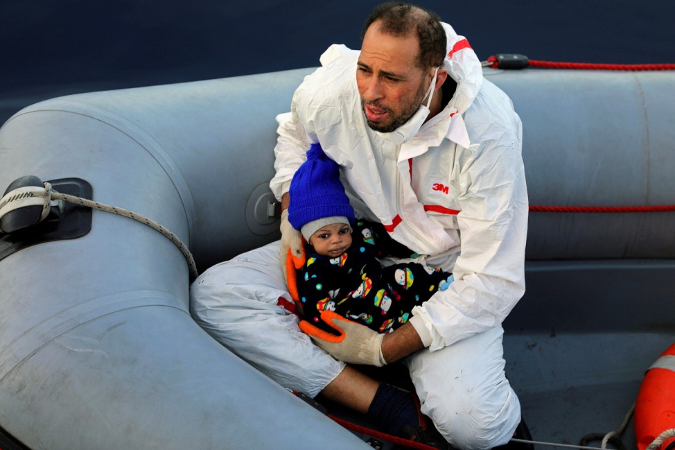 A member of a rescue team carries a migrant baby after being rescued by Libyan coast guards in the Mediterranean Sea off the coast of Libya