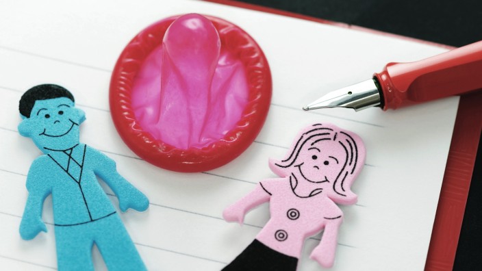 Figuren von Mann und Frau und Kondom in einem Heft Symbolfoto Sexualkundeunterricht McPODE McPODE