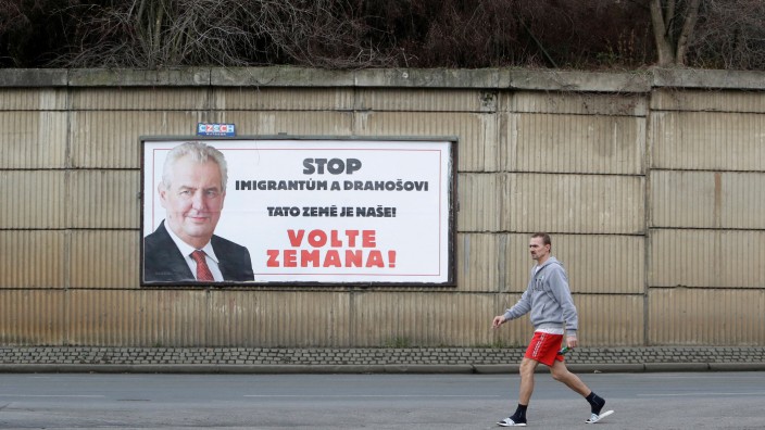A man walks past a poster promoting the incumbent president Milos Zeman in Prague