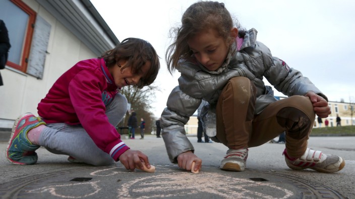 Children of migrants use chalk while playing in refugee deportation registry centre in Manching