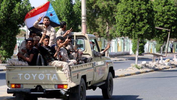 Southern Yemeni separatist fighters flash the V sign as they ride on the back of a truck in Aden
