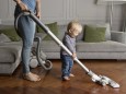 Laughing toddler helping his mother hoovering wooden floor model released Symbolfoto property releas