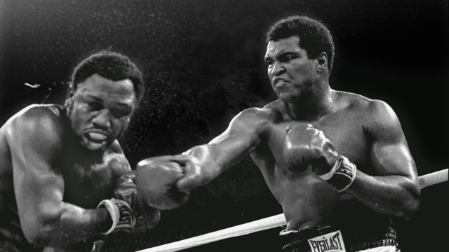 US-Sport: „Thrilla in Manila“: Nach dem Kampf gegen Joe Frazier 1975 kann Muhammad Ali (rechts) bei einem Festmahl vor Schmerzen die Gabel nicht mehr halten.