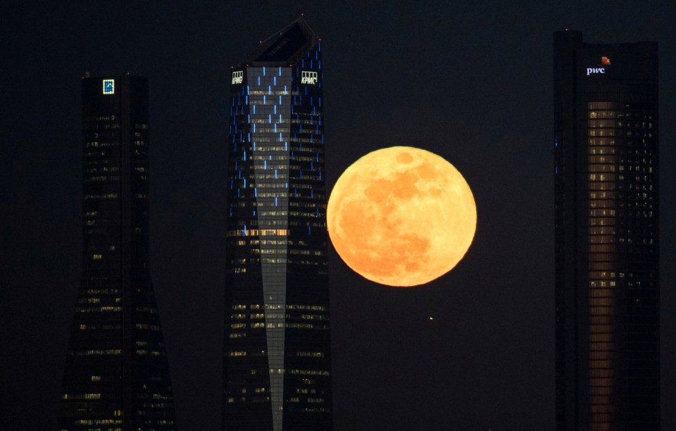 A full moon 'supermoon' rises in between four towers in a skyscrapers area in Madrid