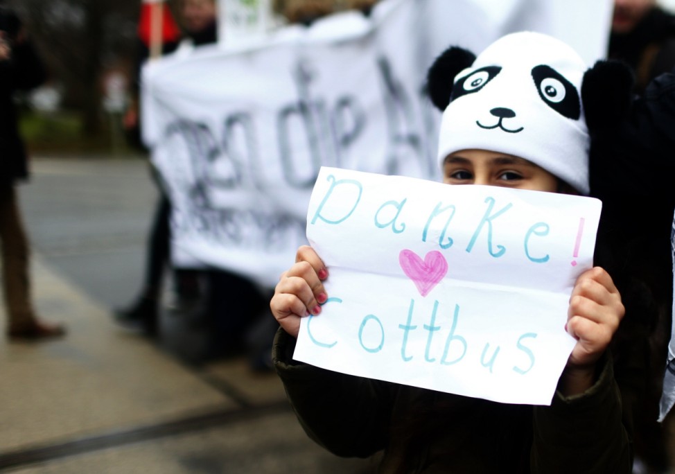 A child holds placard during the demonstration against discrimination of migrants in Cottbus