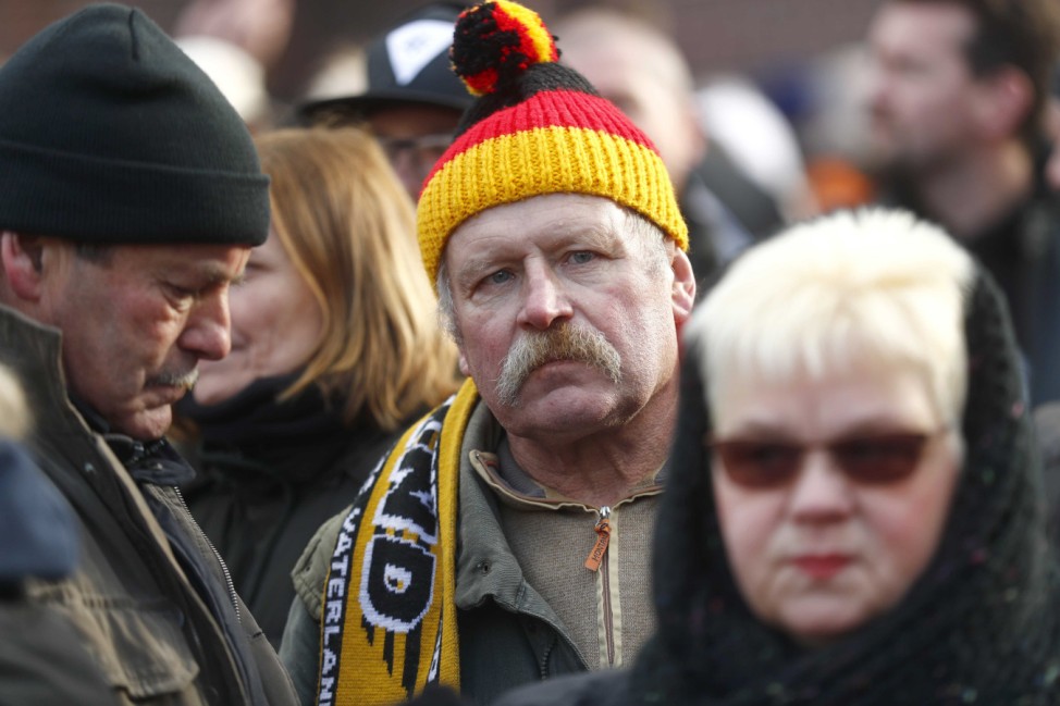 A man wears a hat in German flag colors as he attends a demonstration against migrants in Cottbus