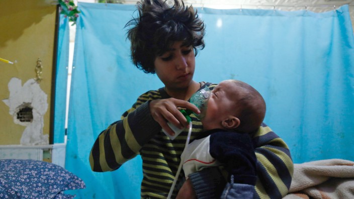 Syrien: Ein syrischer Junge bedeckt das Gesicht eines Kindes nach einem mutmaßlichen Gasangriff im Januar 2018 mit einer Sauerstoffmaske.