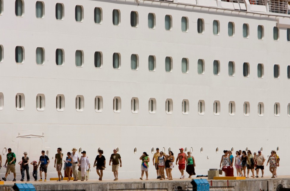 FILE PHOTO: Tourists walk beside Royal Caribbean's cruise ship ?Enchantment of the Seas? after they arrive in Cozumel
