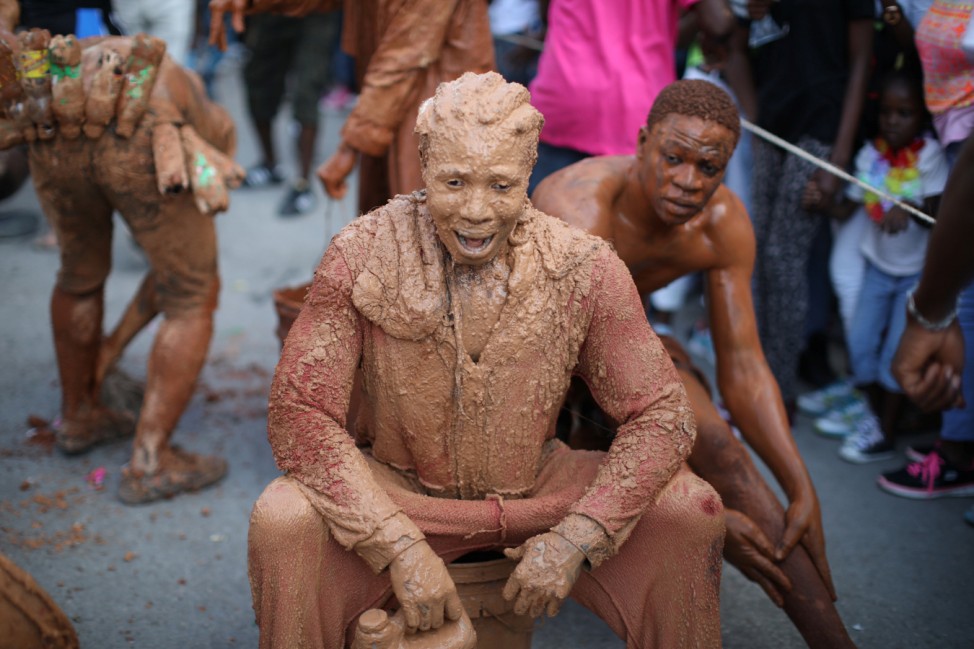 Revellers covered in mud parade along a street at the Carnival of Jacmel