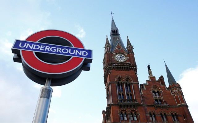 The St Pancras clock tower is seen by an Underground tube sign, London