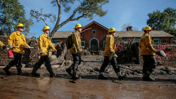 Rescue workers enter properties to look for missing persons after a mudslide in Montecito, California,