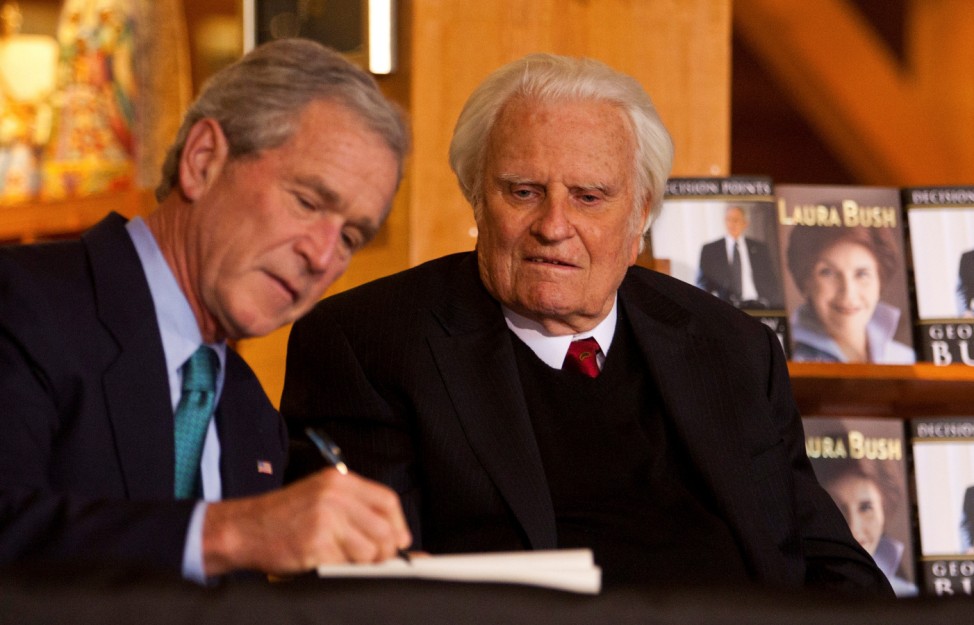 FILE PHOTO: Former U.S. President George W. Bush signs a copy of his new book for Billy Graham at the Billy Graham Library in Charlotte
