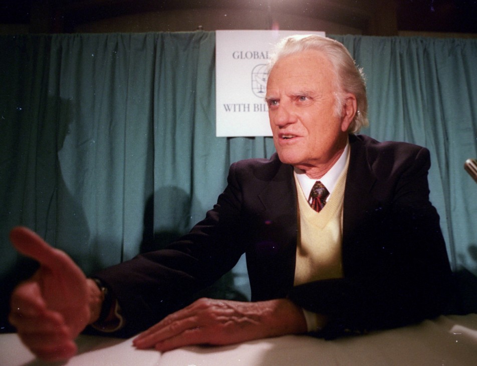 FILE PHOTO: Evangelist Billy Graham talks with a supporter after a New York press conference where he announced a global mission via satellite