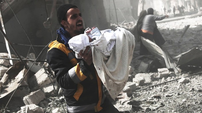 Krieg in Syrien: Ein Syrer rettet einen Säugling aus einer bombardierten Zone in Hamouria, Ost-Ghouta.