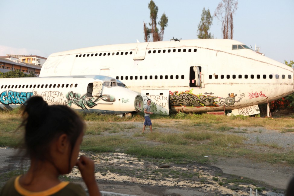 A tourist flies a drone near broken airplanes as he visits the Airplane Graveyard in Bangkok