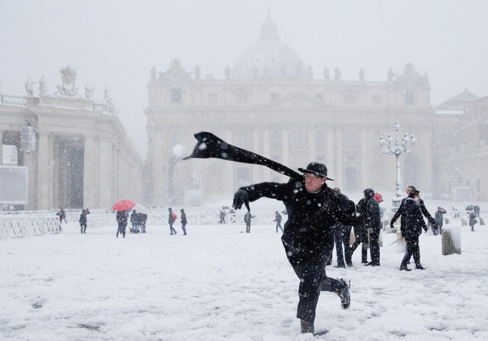 A young priest throws a snow ball during a heavy snowfall in Saint Peter's Square at the Vatican