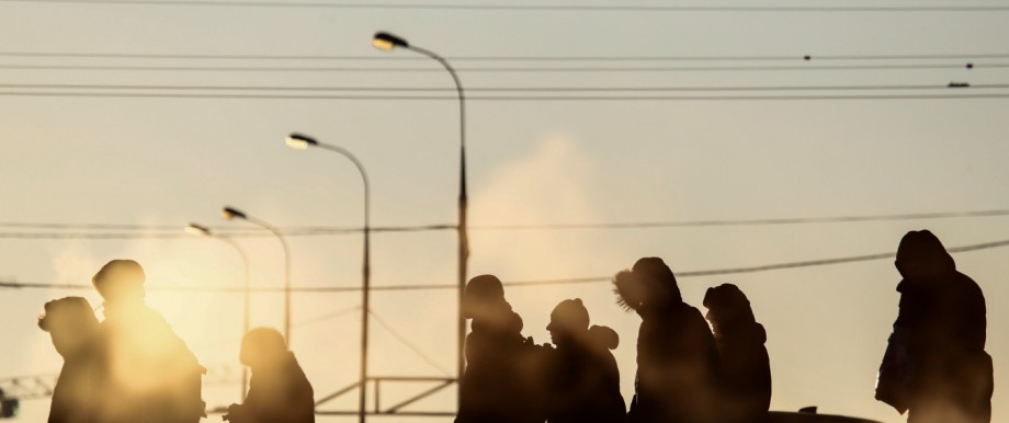 People are silhouetted as they wait at a public transport stop on a frosty winter day in Moscow