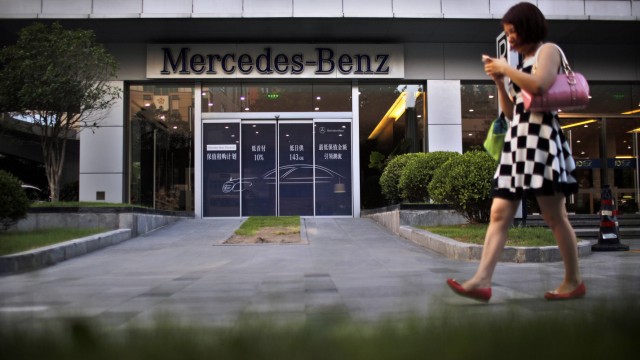 A woman walks past a Mercedez-Benz car dealership in downtown Shanghai