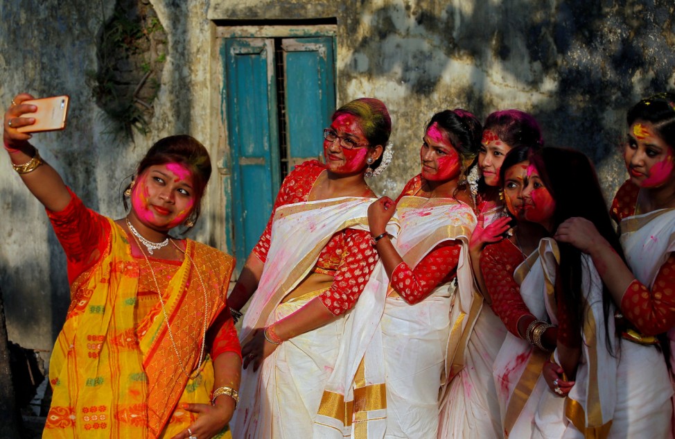 Students of Rabindra Bharati University, with their faces smeared in coloured powder, take a selfie during celebrations for Holi inside the university campus in Kolkata