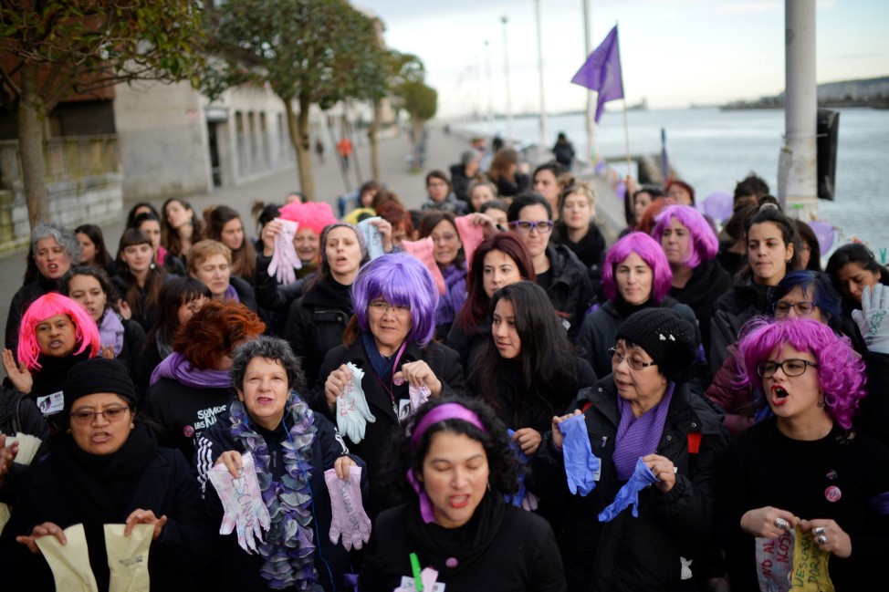 Protesters hold up gloves while taking part in a strike for women's rights in Portugalete