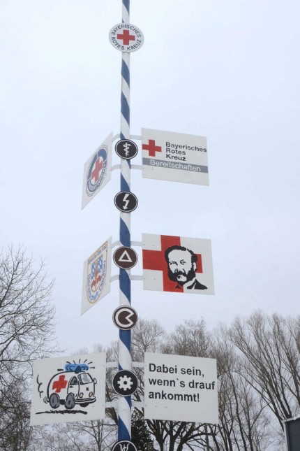 Auf Einsatzfahrt mit dem BRK: "Dabei sein, wenn's drauf ankommt!". Dieser Slogan, einige Symbole und ein Porträt des Begründers des Internationalen Roten Kreuzes, Henry Dunant, schmücken den Maibaum vor der Rettungswache in Gröbenried.
