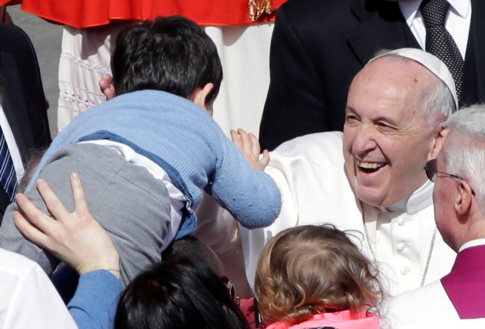 Pope Francis greets a child at the end of the Easter Mass at St. Peter's Square at the Vatican