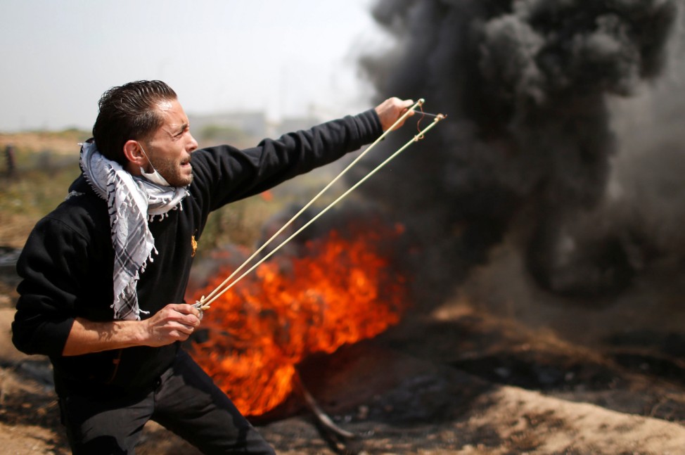 Palestinian demonstrator hurls stones at Israeli troops during clashes at the Israel-Gaza border east of Gaza City